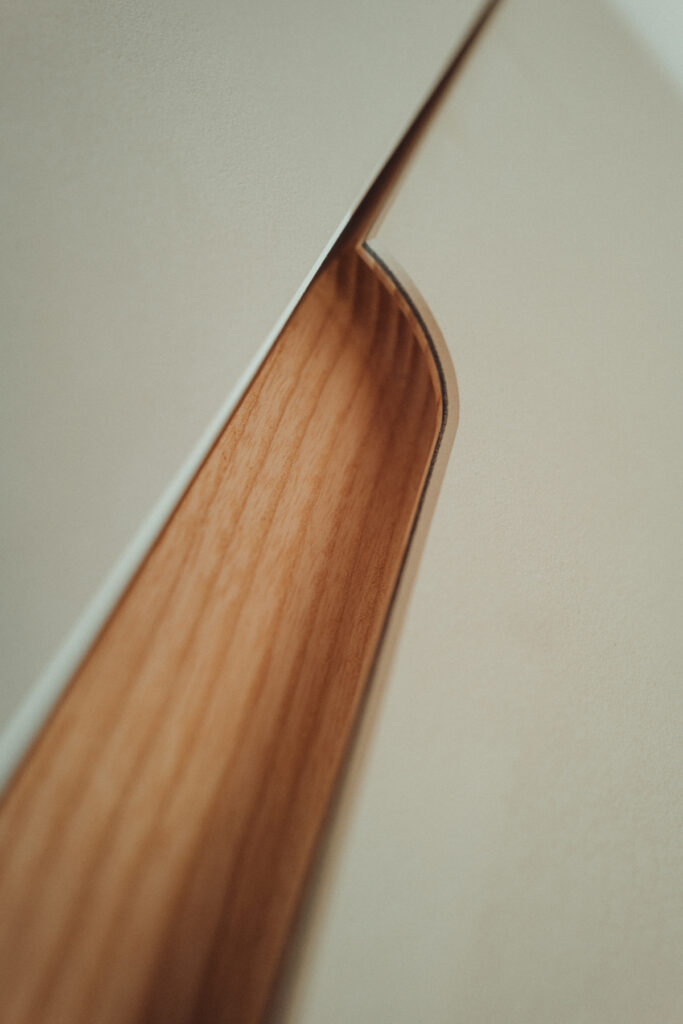 Eck-Einbauschrank nach Maß aus Esche und Linoleum mit warmer LED-Innenbeleuchtung.