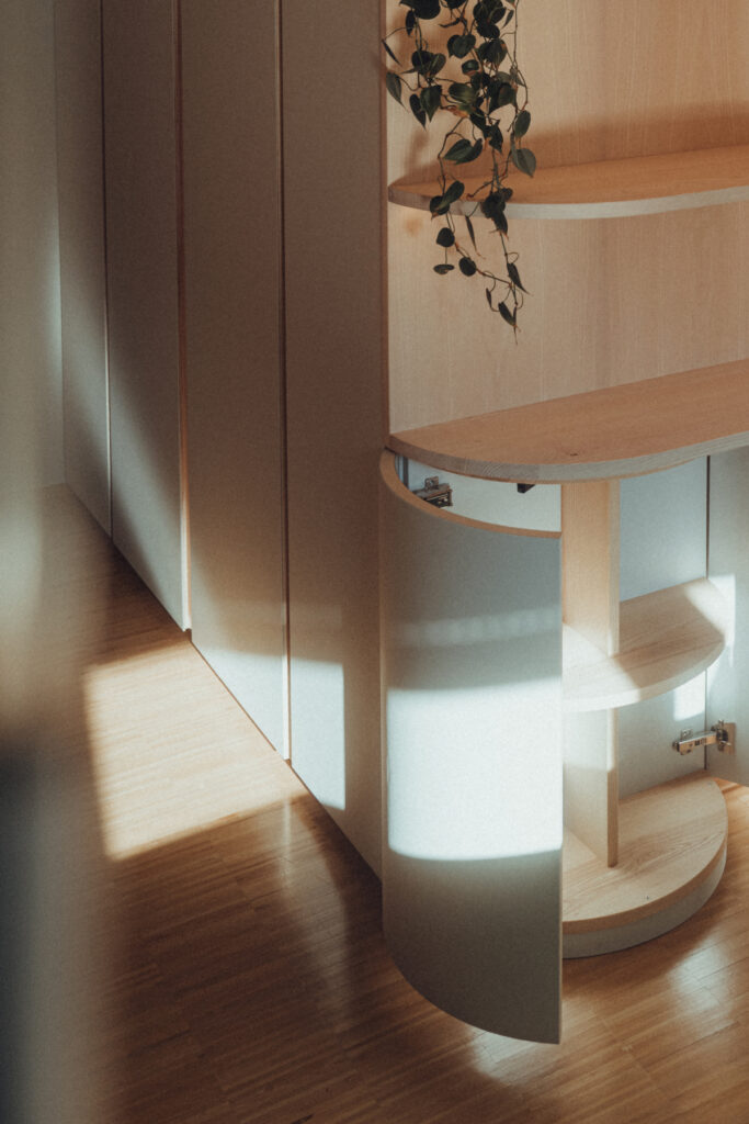 Eck-Einbauschrank nach Maß aus Esche und Linoleum mit warmer LED-Innenbeleuchtung.