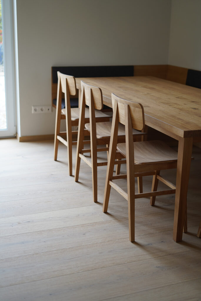 Schwebende Ecksitzbank aus massiver Eiche mit grauer Polsterung und passendem Esstisch für acht Personen.