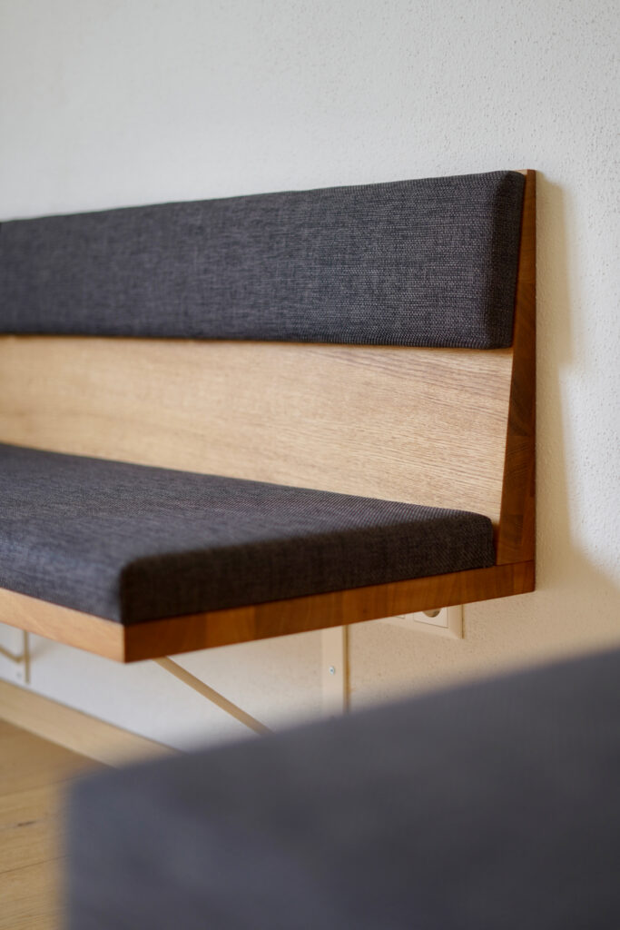 Schwebende Ecksitzbank aus massiver Eiche mit grauer Polsterung und passendem Esstisch für acht Personen.