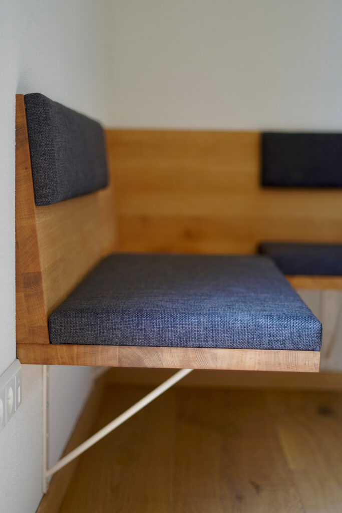 Schwebende Ecksitzbank aus massiver Eiche mit grauer Polsterung und passendem Esstisch für acht Personen.