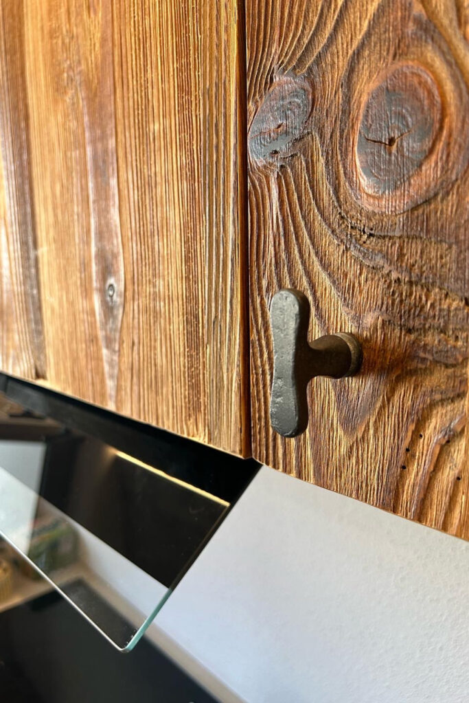 Individuelle Altholzküche mit Rohstahl-Elementen und maßgefertigtem Gewürzregal.