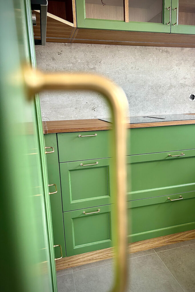 Kompakte Landhausküche in Grün mit Tresen aus Altholz und Eichenelementen.