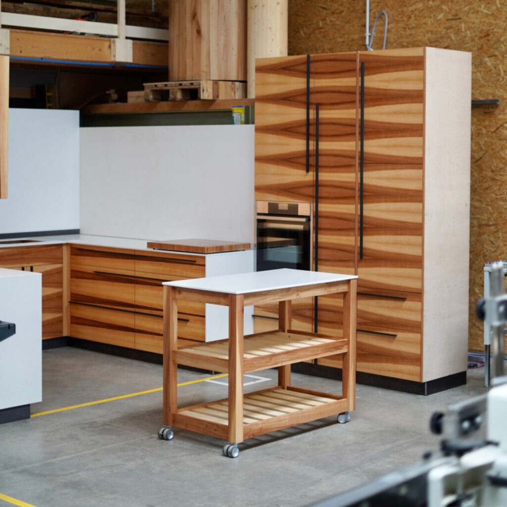 Großzügige Küche aus Apfelholz-Fronten mit einer Arbeitsplatte aus weißem Mineralwerkstoff.