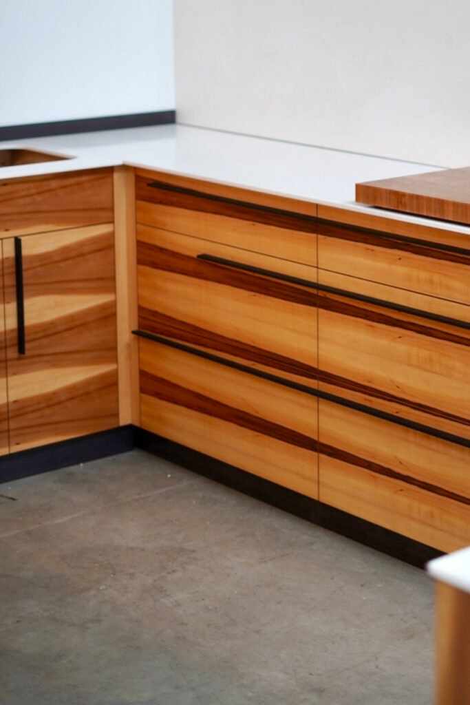 Großzügige Küche aus Apfelholz-Fronten mit einer Arbeitsplatte aus weißem Mineralwerkstoff.