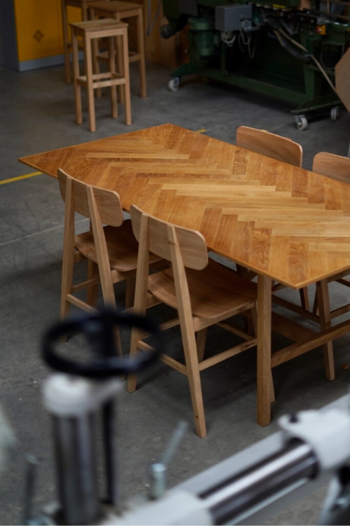 Esstisch Essenz aus massiver Eiche mit einer Tischplatte aus Fischgrät-Parkett und filigranen Beinen.