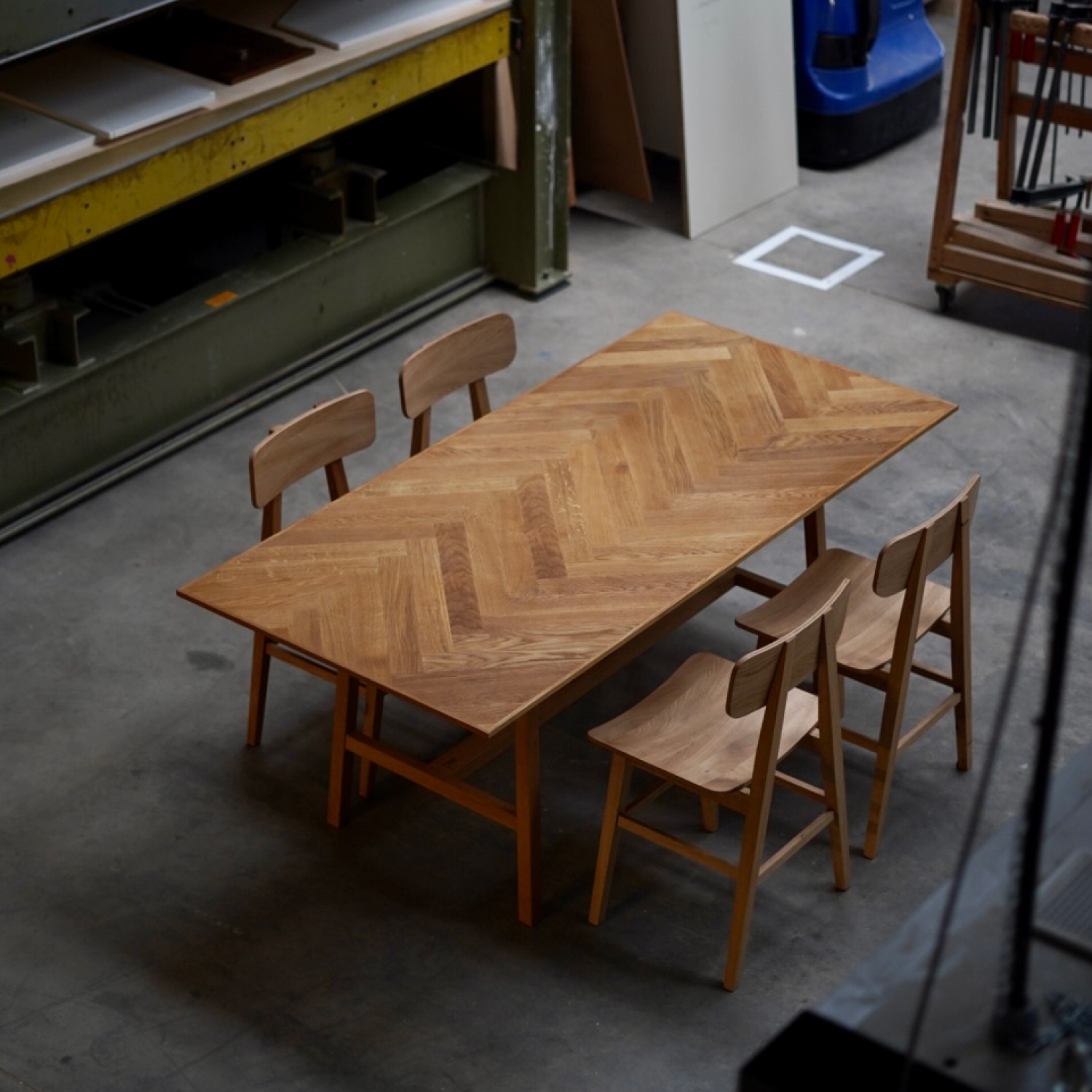 Esstisch Essenz aus massiver Eiche mit einer Tischplatte aus Fischgrät-Parkett und filigranen Beinen.