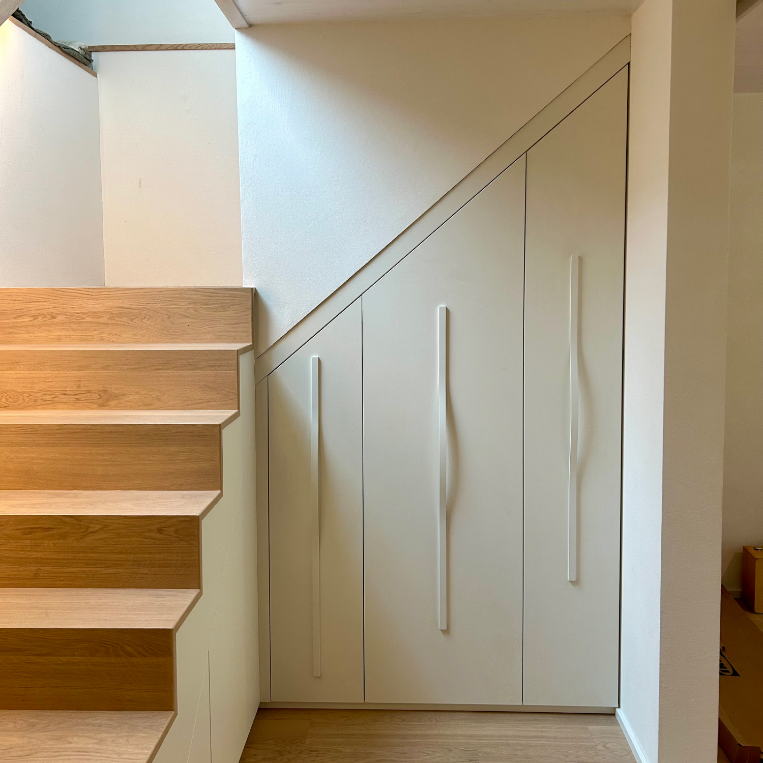 Einbau-Treppenschrank aus Eiche mit indirektem Lichtband am Handlauf.