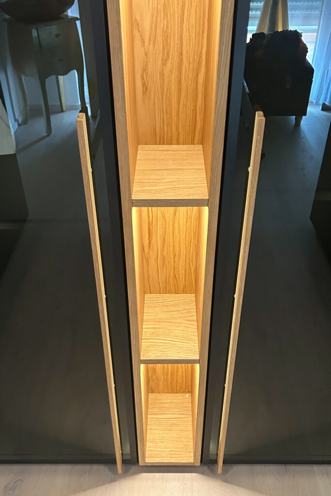 Begehbare Ankleide in U-Form aus Eiche und Schwarzglas mit smarter Innenbeleuchtung und spezialisierten Schubladen.