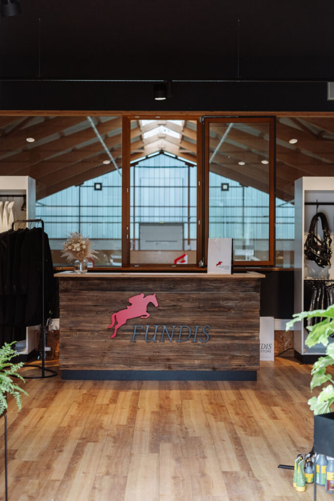 Exklusive Ladeneinrichtung aus Altholz, Eiche und Stahl für einen Reitsport-Shop mit Blick in die Reithalle.