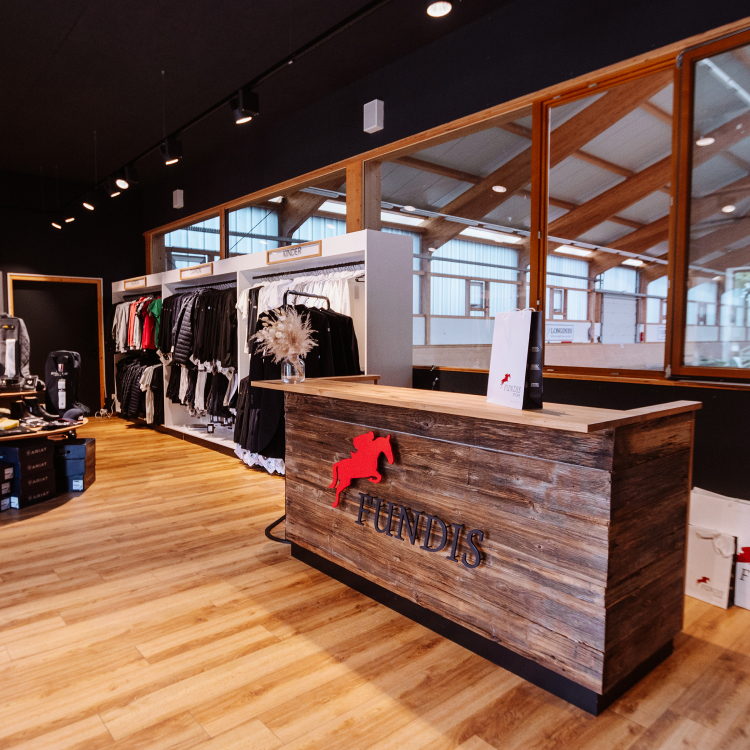 Exklusive Ladeneinrichtung aus Altholz, Eiche und Stahl für einen Reitsport-Shop mit Blick in die Reithalle.