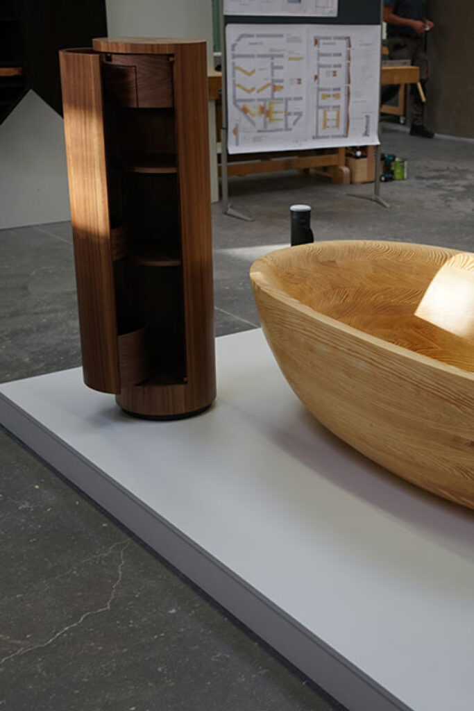 Exklusives Bad-Ensemble aus Nussbaum und Carolina Pine: Freistehende Badewanne und zylindrischer Waschtischunterschrank mit mechanischem Holz-Verschluss.