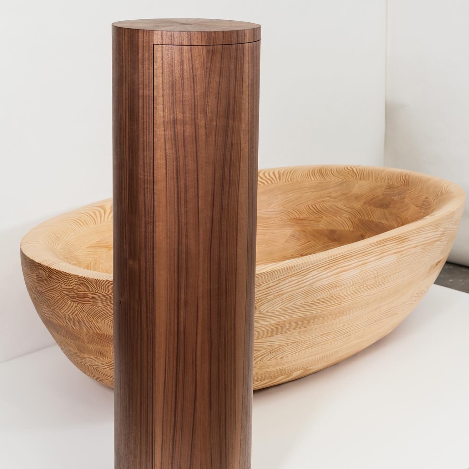 Exklusives Bad-Ensemble aus Nussbaum und Carolina Pine: Freistehende Badewanne und zylindrischer Waschtischunterschrank mit mechanischem Holz-Verschluss.